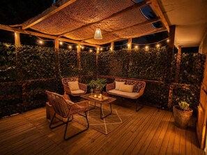 A covered outdoor seating area with wicker furniture, string lights, and a wooden floor. - Appartement avec terrasse privée , parking privé, à 7 min des Thermes de Saujon (Saint-Romain-de-Benet)