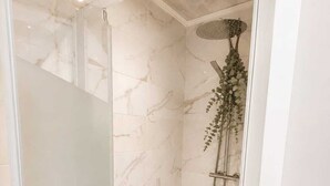 A glass-enclosed shower with a wooden stool, a hanging shower head, and a marble wall. - Appartement avec terrasse privée , parking privé, à 7 min des Thermes de Saujon (Saint-Romain-de-Benet)