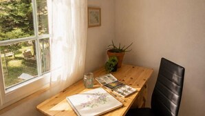 A room with a wooden desk, a black chair, a window with white curtains, and a potted plant. - Appartement avec terrasse privée , parking privé, à 7 min des Thermes de Saujon (Saint-Romain-de-Benet)