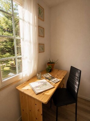 A room with a wooden desk, a black chair, a window with white curtains, and a potted plant. - Appartement avec terrasse privée , parking privé, à 7 min des Thermes de Saujon (Saint-Romain-de-Benet)