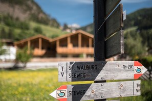 A wooden directional signpost with destinations and distances. - Sunnseit Luxury Apartment with Lake View, Balcony, and Wi-Fi (Pracupola)