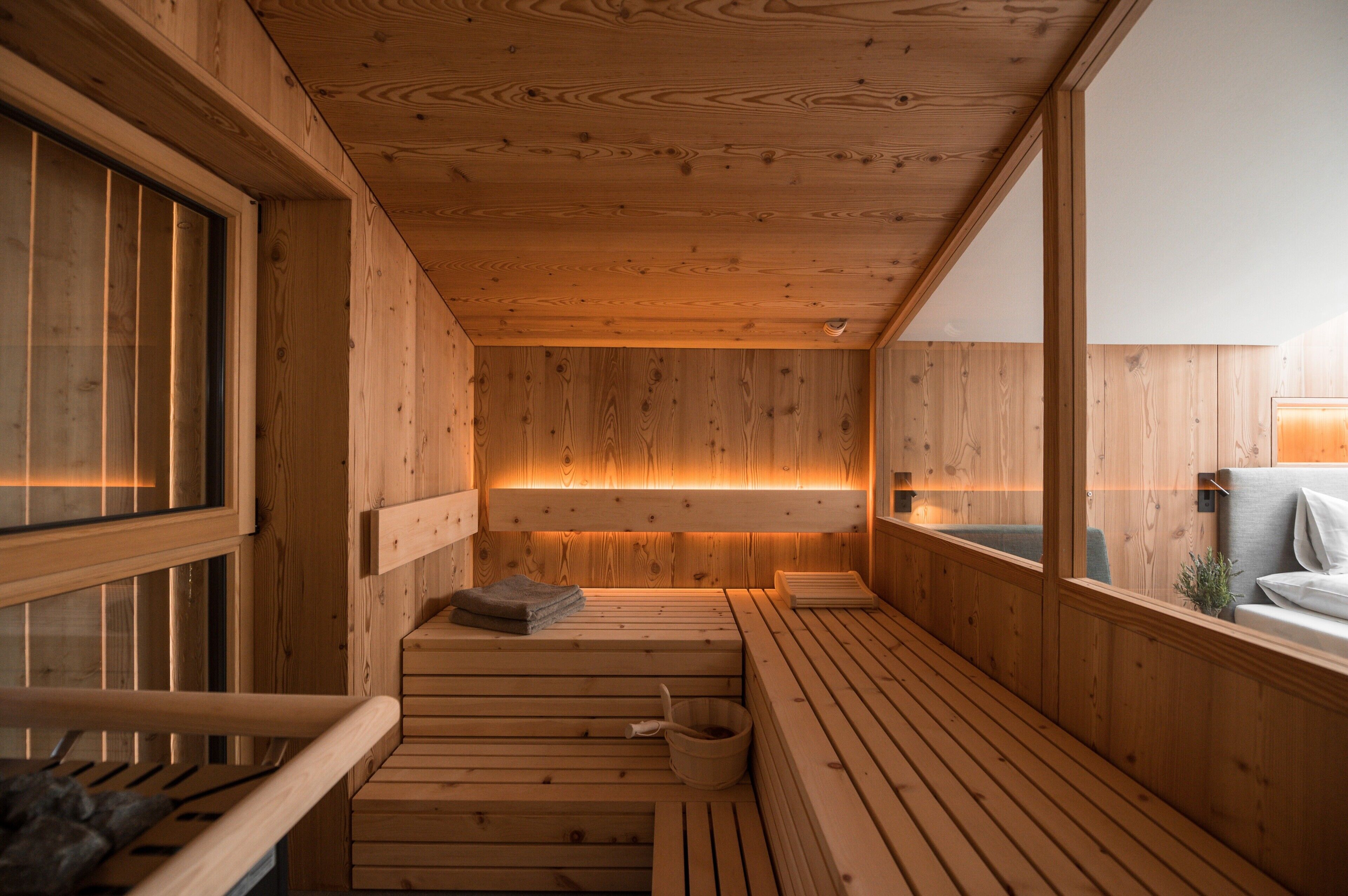 A wooden sauna with benches, a bench with a towel, and a window.