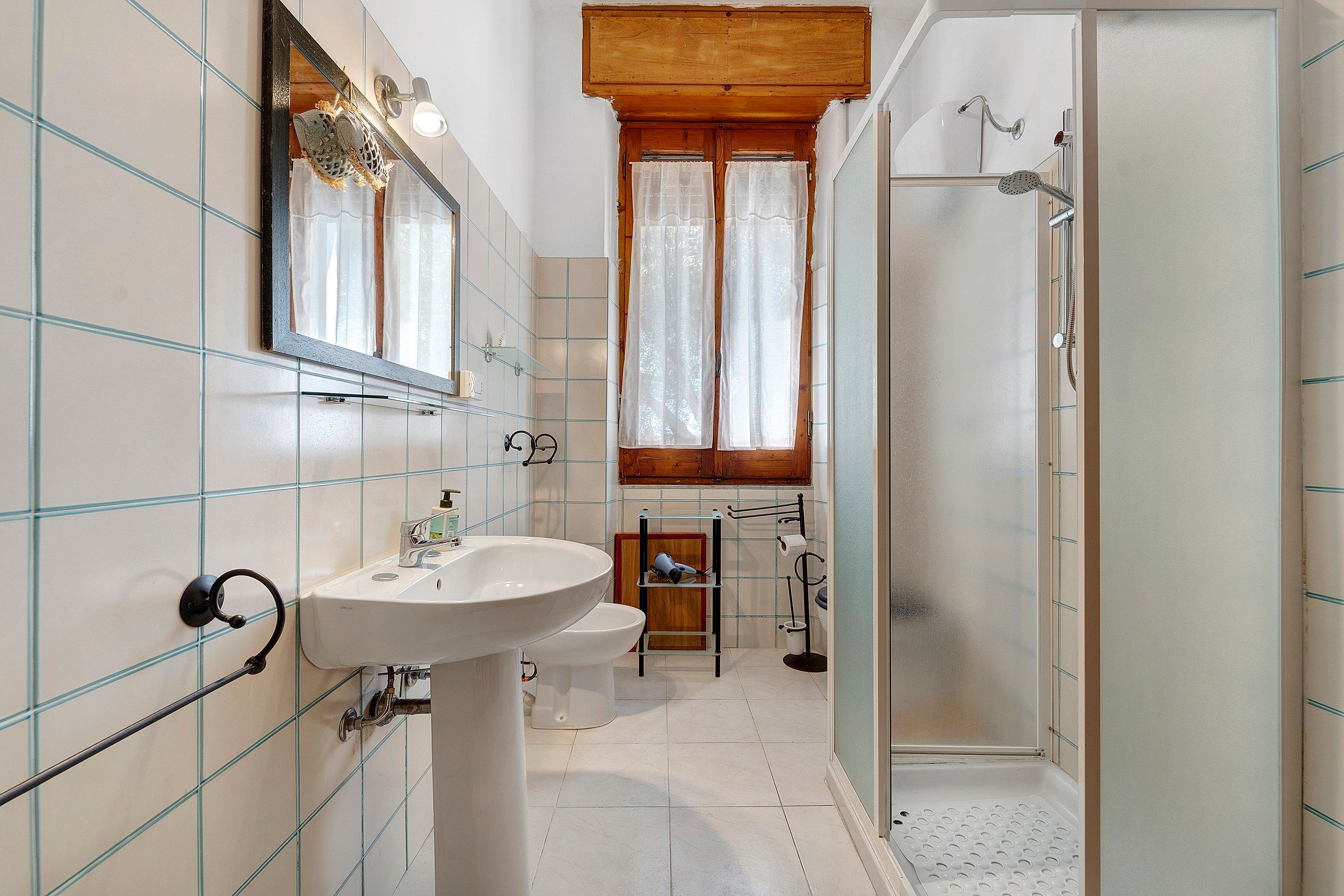 Une salle de bain équipée d’un lavabo, d’un miroir, d’une douche et de toilettes.