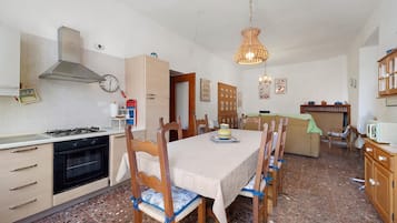 Eine Küche mit Esstisch, Stühlen, Herd, Backofen und einer Pendelleuchte.