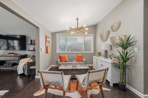 A modern living room with a dining area, a television, and a kitchen in the background. - The Murray, Modern Retreat, Spa & Billiards (San Diego)