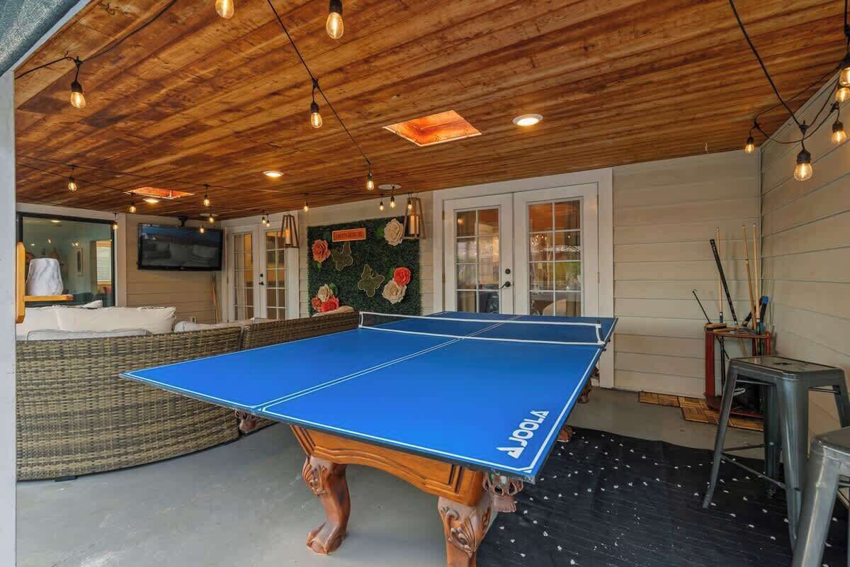 Una mesa de ping pong en una habitación con techo de madera y un televisor montado en la pared.