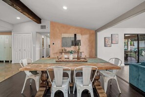 A dining area with a large wooden table, white chairs, and a central decorative piece. - The Murray, Modern Retreat, Spa & Billiards (San Diego)