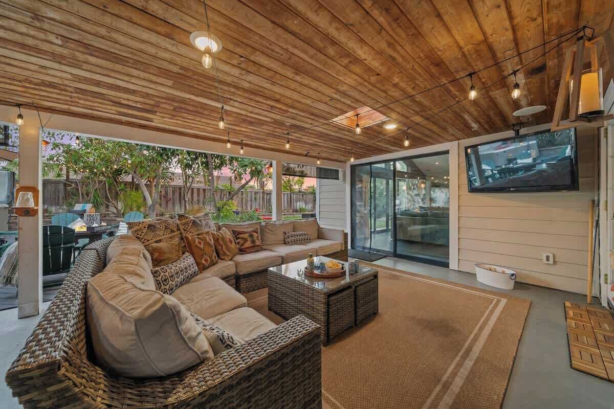 A modern living room with a large sectional sofa, a coffee table, and a flat-screen TV mounted on the wall.