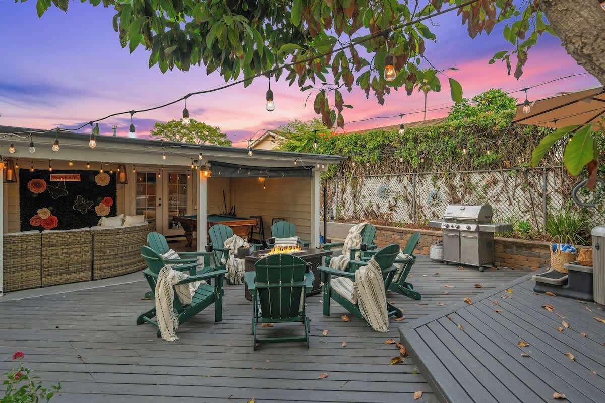 A deck with green chairs, a table, and a barbecue grill.