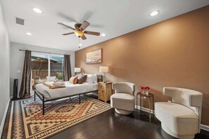 A bedroom with a bed, two chairs, a nightstand, a lamp, and a ceiling fan. - The Murray, Modern Retreat, Spa & Billiards (San Diego)