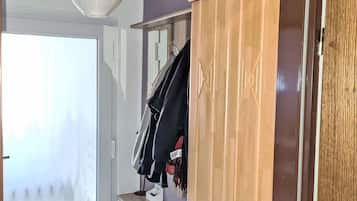 Ein Zimmer mit einem Holzschrank, einem kleinen Nachttisch mit Schublade und einem Kleiderhaken.
