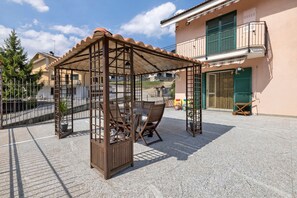 A covered outdoor seating area with metal furniture and a pergola structure.