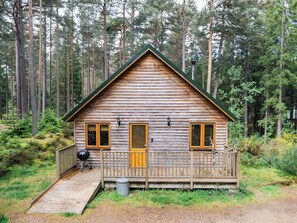 Eine Holzhütte mit Veranda, Grill und kleiner Terrasse.