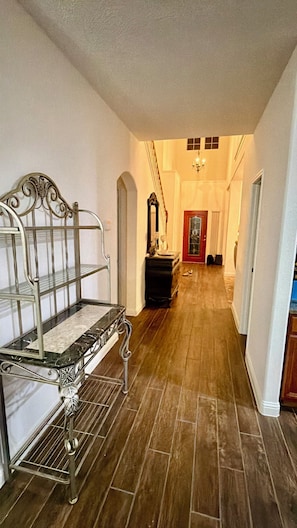 A hallway with a metal bench, a dresser, and a door at the end. - This spacious house has 5 bedrooms and 2.5 bathrooms, along with many amenities. (Houston)