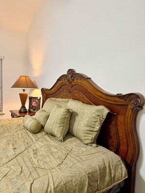 A bed with a wooden headboard, a bedside table with a lamp, and a framed picture. - This spacious house has 5 bedrooms and 2.5 bathrooms, along with many amenities. (Houston)
