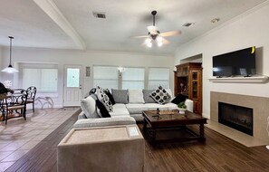 A living room with a sofa, coffee table, fireplace, and a television. - This spacious house has 5 bedrooms and 2.5 bathrooms, along with many amenities. (Houston)