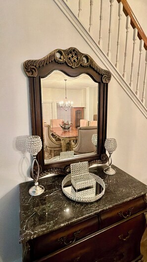 A dark wooden dresser with a mirror, two crystal candle holders, and a crystal tray. - This spacious house has 5 bedrooms and 2.5 bathrooms, along with many amenities. (Houston)