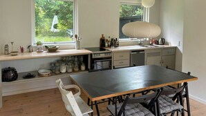 Eine moderne Küche mit Essbereich, großen Fenstern und Blick auf Grünflächen.