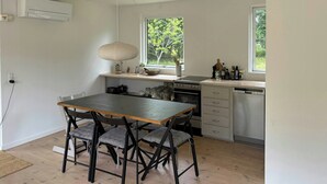 Eine kleine Küche mit Esstisch und Stühlen, einem Fenster und einem eingebauten Backofen.