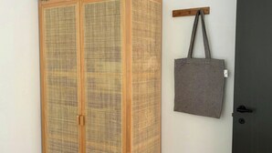 Ein Zimmer mit einem Holzschrank, einer grauen Tragetasche, die an einem Haken hängt, und einer dunklen Tür.