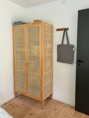 A room with a wooden wardrobe, a grey tote bag hanging on a hook, and a dark door. - Bright 1960s house with natural plot near beach (Højbyb)