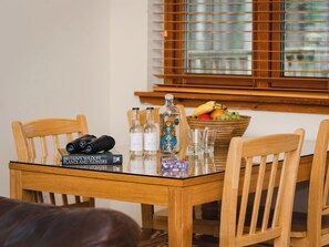 Een houten eettafel met een boek, verrekijkers en flessen.