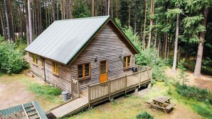 A cabin with a porch, a deck, and a small outdoor seating area. - Cosy apartment for 4 people with TV, patio and pets allowed (Coldstone)