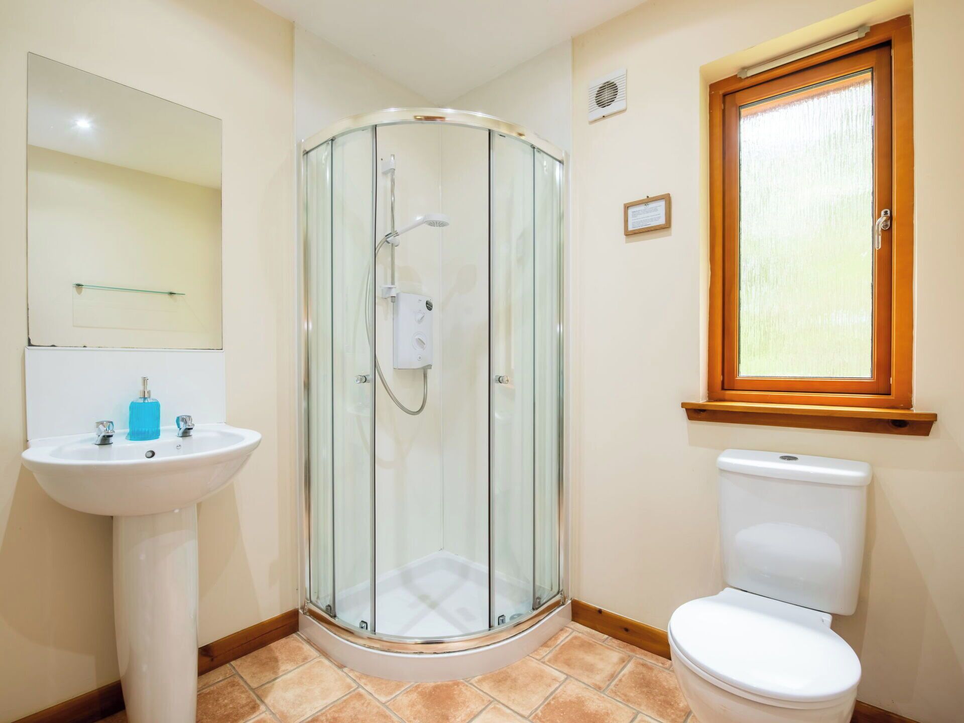 Ein Badezimmer mit Duschkabine aus Glas, einem Standwaschbecken und einer Toilette.
