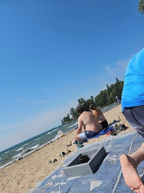 A beach with a clear sky, a sandy shore, and a few people.