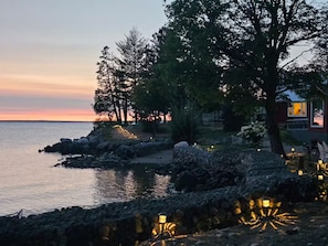 A coastal property with a stone pathway, trees, and a view of the sea.