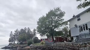 A waterfront property with a house, a dock, and a rocky shoreline.