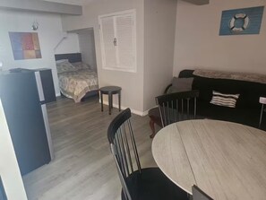 A compact living space with a kitchenette, a bed, a dining area with a round table, and a sofa.