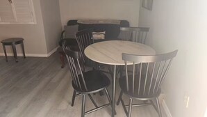 A dining area with a round table and six chairs, a sofa, and a small table with a chair.