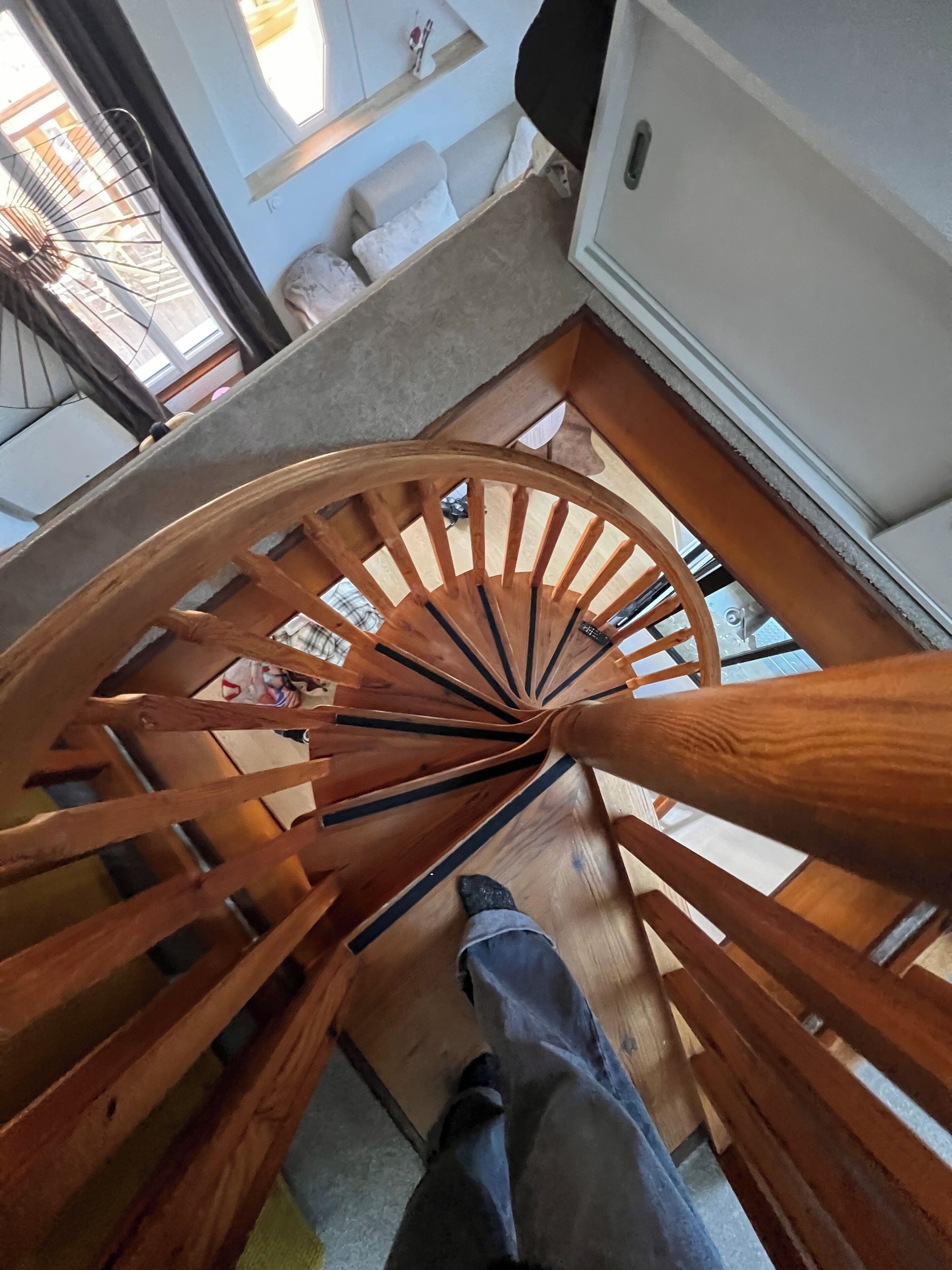 Een houten spiraaltrap met iemand die onderaan staat.