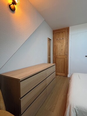 Ein Schlafzimmer mit einem hölzernen Schminktisch, einem Bett und einem Holzschrank.