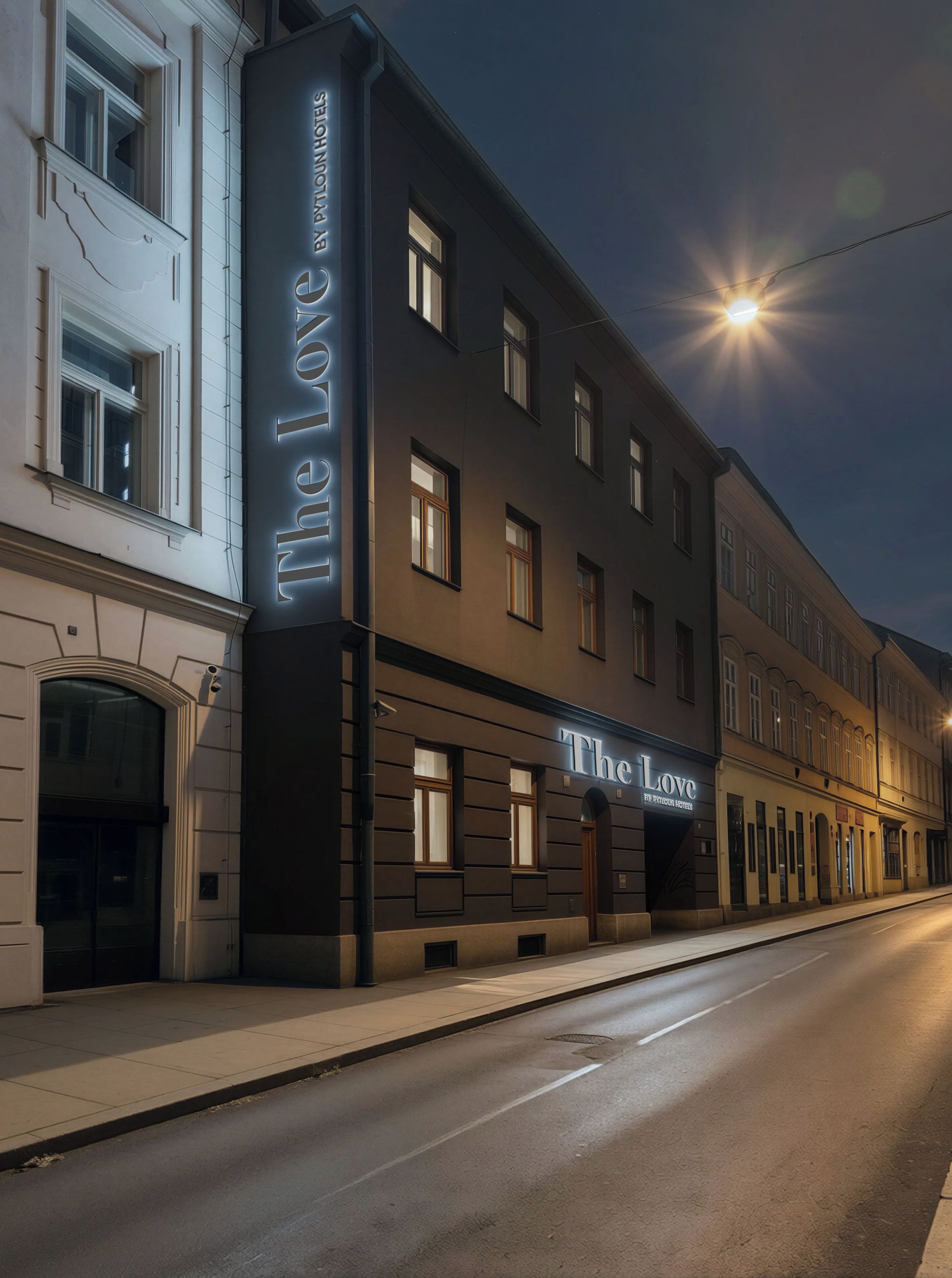 A hotel facade with illuminated signage, a street view, and a clear sky.