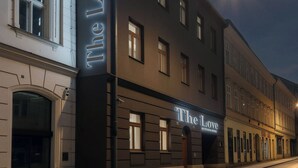 En hotels facade med oplyst skiltning, et gadesyn og en klar himmel.