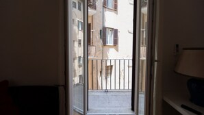 En åben dør, der fører ud til en balkon med udsigt til omkringliggende bygninger.