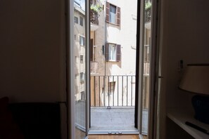 Eine offene Tür, die zu einem Balkon mit Blick auf benachbarte Gebäude führt.