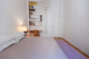Ein Schlafzimmer mit Bett, Schreibtisch, Stuhl, Bücherregal und einer Tür.