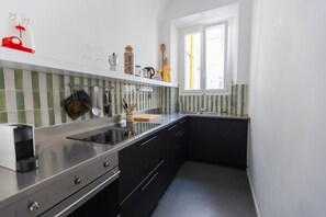 Moderni keittiö, jossa on musta työtaso, ruostumattomasta teräksestä valmistetut kodinkoneet ja ikkuna, josta tulee luonnonvaloa.