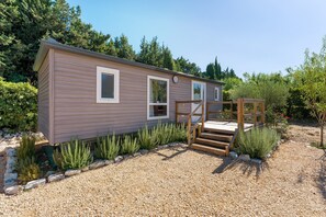 Une maison mobile de plain-pied, avec une allée en gravier et un escalier en bois menant à un porche.