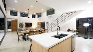 Una cucina moderna con isola centrale, zona pranzo e una scala che conduce a un piano superiore.