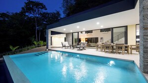 Una casa moderna con piscina, area salotto esterna e una scala che conduce a un piano superiore.