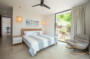 Une chambre moderne avec un grand lit, une chaise et une vue sur la verdure.