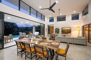 A spacious dining area with a large table and chairs, a ceiling fan, and a view of the outdoors. - New Listing • Casa Azul Oasis • Pacifico 4BR Villa • Private Pool (Playas del Coco)