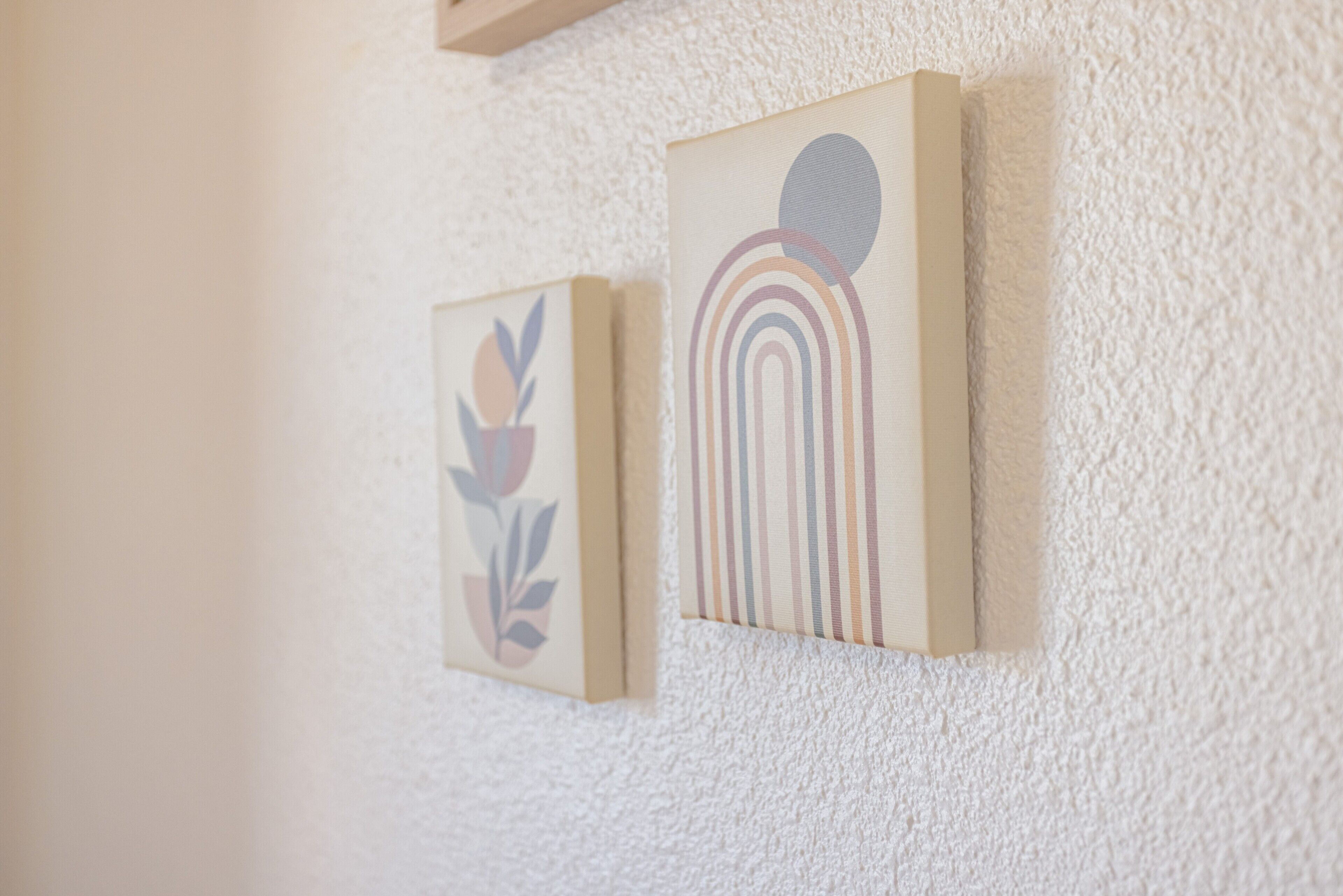 Two framed artworks on a textured wall.