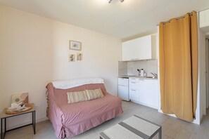 Ein Schlafzimmer mit einem Bett, einem kleinen Tisch, einer Küchenzeile und einem Badezimmervorhang.