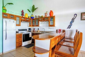 Eine Küche mit Holzausstattung, einem Kühlschrank, einem Herd und einer Bar mit Hockern.