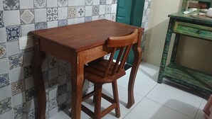 Una mesa y una silla de madera en una habitación con baldosas estampadas y una puerta verde.
